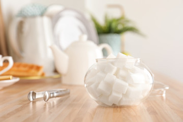 Fototapeta na wymiar Glass bowl with white sugar cubes on wooden table