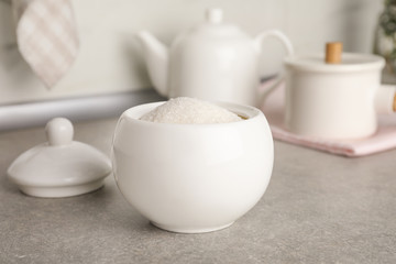 Ceramic bowl with white sugar on grey table