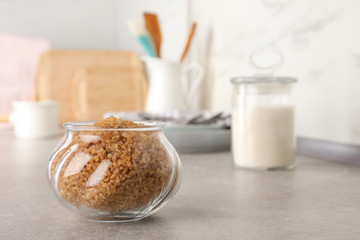 Glass bowl with brown sugar on grey table