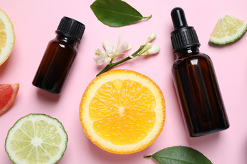 Flat lay composition with bottles of citrus essential oil on pink background
