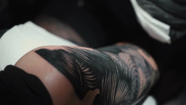 Shooting of man doing black tattoo of snake for woman in studio
