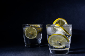  splash Gin and tonic cocktail with lemon slices Ice cube falls into water with lemon Copy space,...