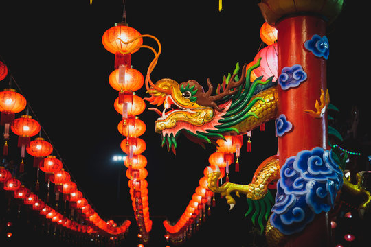 Dragon head sculpture on the post with Chinese lanterns at night.
