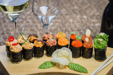Set of several different rolls on a wooden stand on a table in a Japanese restaurant. Japanese traditional sushi and rolls.