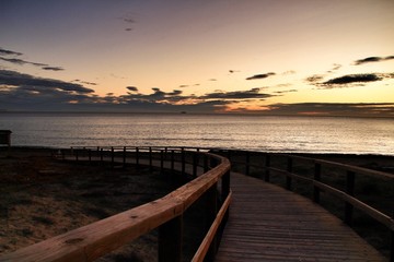 Fototapeta na wymiar Wooden walkway to the beach at sunrise in Alicante, Spain