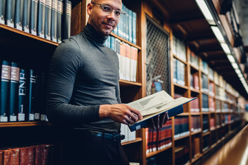 Half length portrait of intellectual professor of history in bifocal eyewear looking at camera...