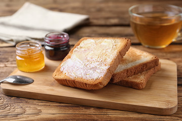 Fototapeta na wymiar Delicious crispy toasts and jams on wooden table
