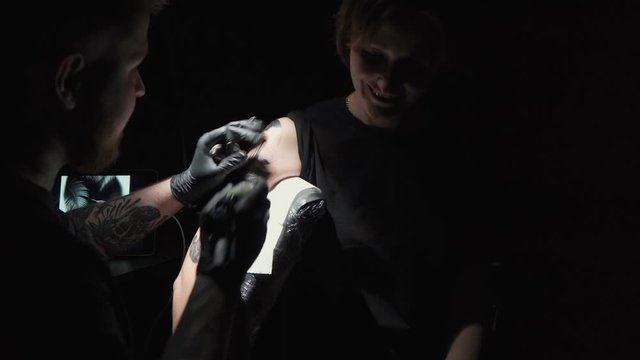 Shooting of doing black tattoo for woman in studio