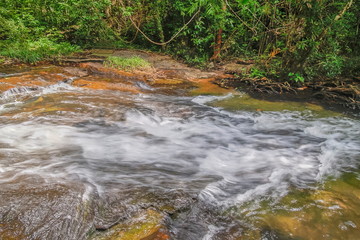 Naklejka na ściany i meble view of stream silky water flowing on rock ground around with green forest background, Pang Sida Waterfalls, Pang Sida National Park, Sa Kaeo Province, eastern of Thailand.