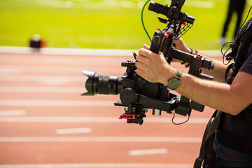 Close-up of camera-man shooting sport track competition view from profile
