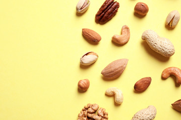 Different delicious nuts on yellow background, flat lay. Space for text