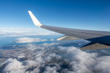 Plane silver wing during a flight over white clouds and a winter land is on the photo