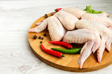 Fresh semi-finished raw chicken wings with pepper lie on a wooden surface