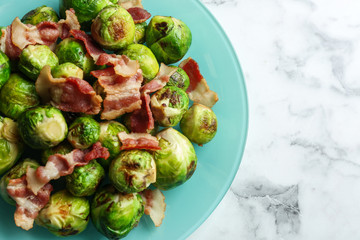 Delicious Brussels sprouts with bacon on white marble table, top view
