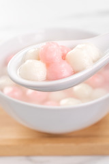 Tang yuan, tangyuan, delicious red and white rice dumpling balls in a small bowl. Asian traditional festive food for Chinese Winter Solstice Festival, close up.