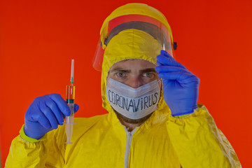 Man in yellow chemical protection suit and face protective mask coronavirus. Without glasses. Protective helmet. Hands in blue gloves. Yellow vaccine syringe.