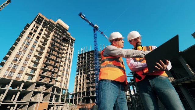 Professional construction engineers, construction architects work on a building site with a laptop.