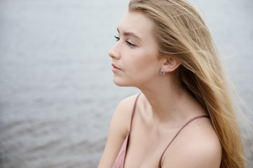 Young woman in pink dress on sand and enjoys sea.