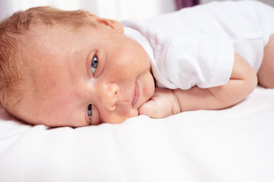 Portrait of newborn infant baby boy laying on the belly close face crop