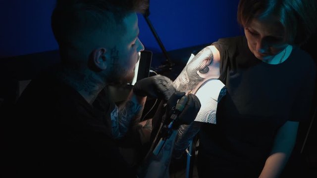 Shooting of doing black and white tattoo of snake on woman in studio
