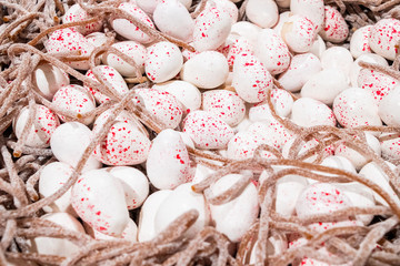 Fresh fragrant pieces of marmalade in the form of white bird eggs in a nest are in a large pile on the counter in the store. Beautiful tasty treat made from natural ingredients.