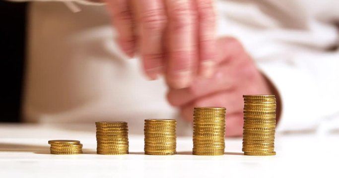Business man stacks money to equal distribution stacks, socialism or gender pay gap concept