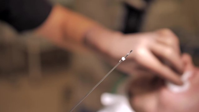 Close-up of cannula ready for Thread Lifting, Doctors hand on a blurred background.