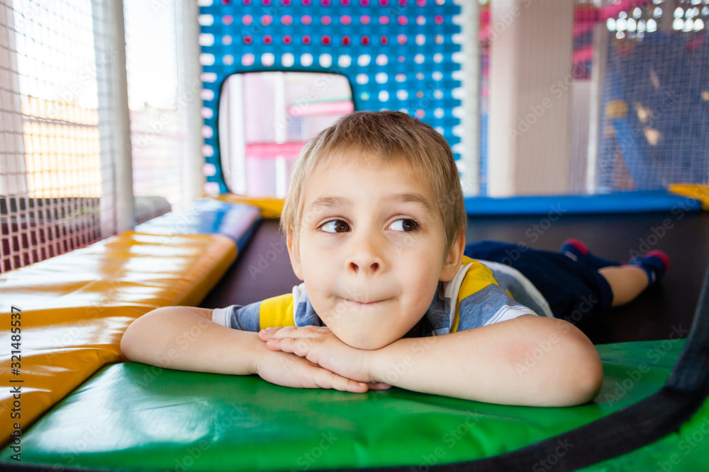 Wall mural Little boy resting on trampoline in play centre