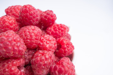 Raspberry berries close-up. fresh raspberries in a white cup on a white background. View from above. Soft focus.