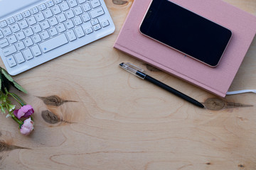 Wooden desktop with keyboard, diary and pen, glasses for the computer. Working environment, receiving calls. Keeping notes, with hands.