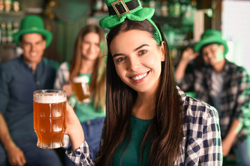 Young woman with beer celebrating St. Patrick's Day in pub