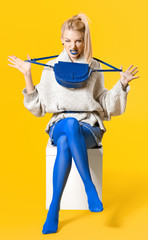 Young woman with creative makeup and in warm sweater on color background