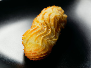 One eclair on a black background. Choux pastry.