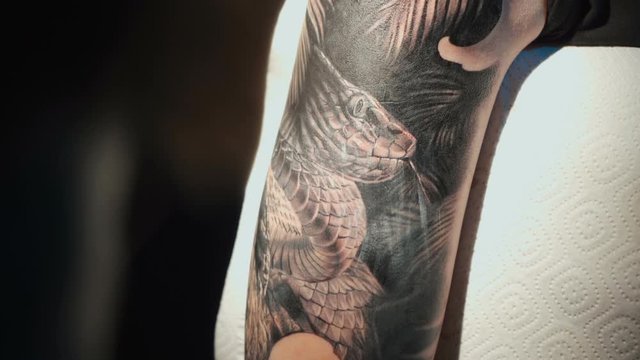 Close up video of doing black tattoo on woman in studio