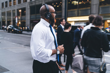 Black executive listening to music while crossing street