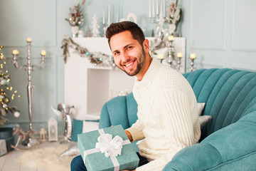 Man in a white sweater holding gift box