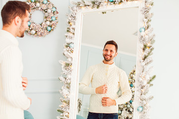 Portrait of young man near large mirror