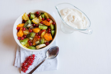 A bowl of fresh berry fruit salad on the white kitchen table. Vegan snack, diet food, healthy food concept.