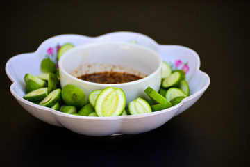 Green sour mango with sweet fish sauce in the dish on black background, Delicious Fruit from Thailand