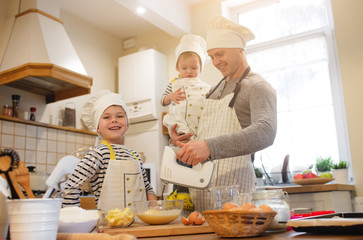 Dad and his sons in chef's hats are cooking