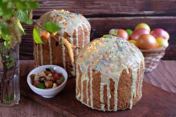 Easter table with two cakes and painted Easter eggs with a birch branch in a vase. The concept of religious holidays, family traditions.