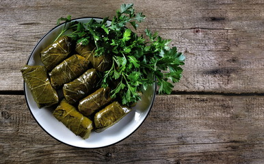  Mediterranean dish Dolmadakia or dolma-grape leaves stuffed with minced meat with rice on a background of old boards. Served with yogurt sauce. Copy space.