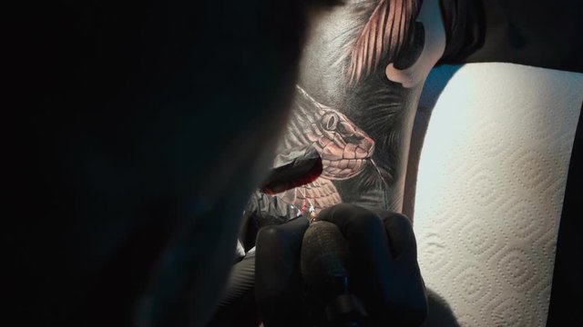 Close up video of man doing tattoo on woman in studio