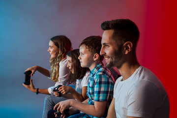 Father, mother and children playing a video game at modern gaming club