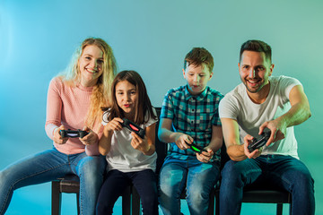 Obraz premium Young cheerful parents and kids playing video game together