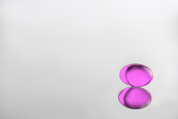 gelatinous pink capsule on a gray background. vitamin