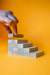 Hand arranging wood block stacking as step stair. Ladder career path concept for business growth success process.