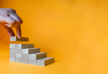 Hand arranging wood block stacking as step stair. Ladder career path concept for business growth success process.