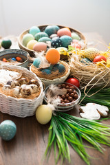 Fototapeta na wymiar Colorful Easter eggs in nest, feathers and spring flowers on wooden table. Easter holiday decorations , Easter concept background.
