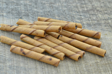 Chocolate waffle roll sticks on wooden background